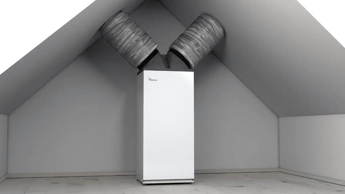 Weißer Kühlschrank mit zwei Lüftungsrohren in einem leeren Dachbodenraum.