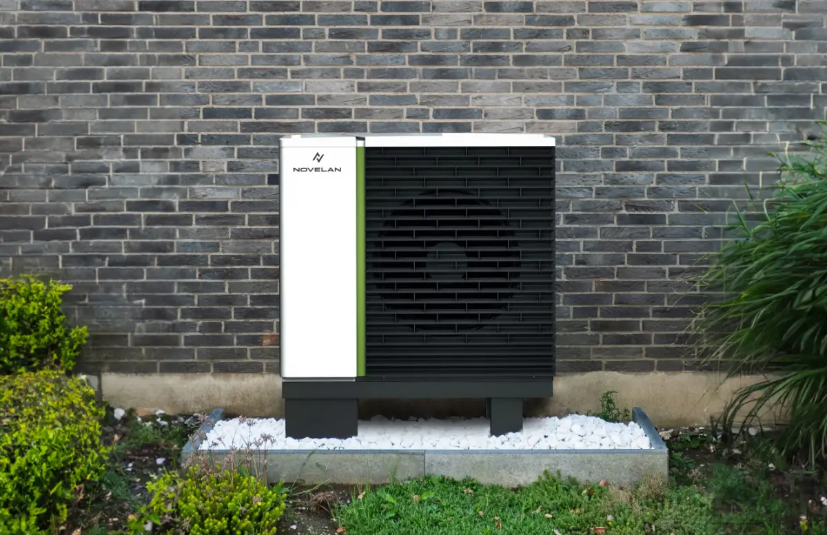 Klimaanlage steht auf einem weißen Sockel vor einer grauen Backsteinwand.